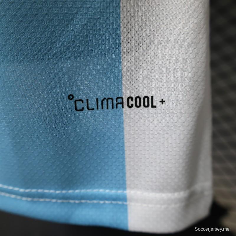 قميص المنتخب الأرجنتيني للمباريات على أرضه، إصدار اللاعب 2027، باللونين الأبيض والأزرق الفاتح مع شارة بطل كأس العالم FIFA